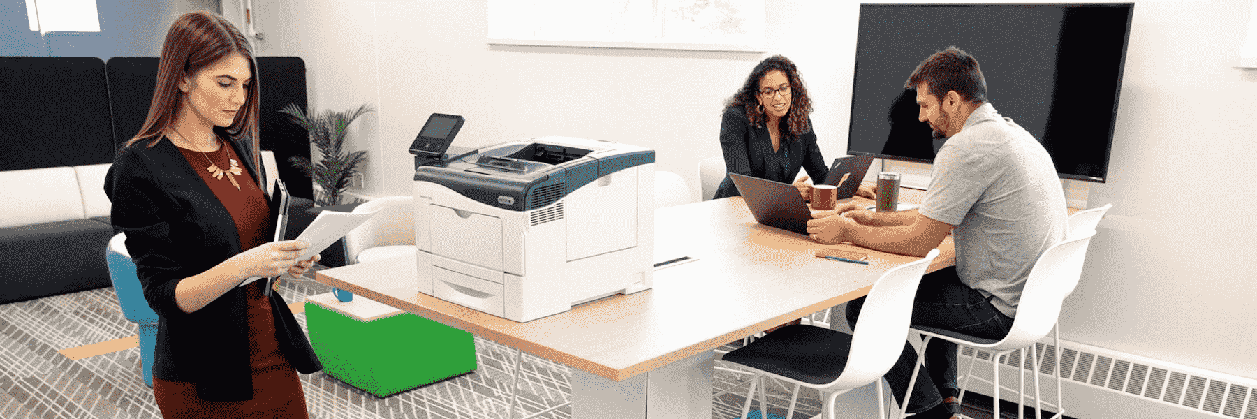 Three people at the office working near a Xerox printer