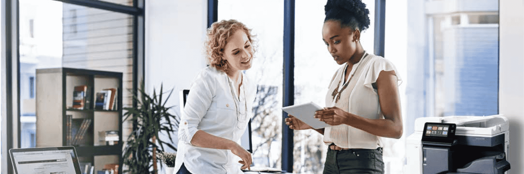 Two people looking at documents with the Xerox VersaLink C7020 in the background