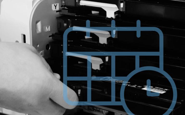 a grayscale image of a hand pulling a toner out of a printer with a calendar graph on top 