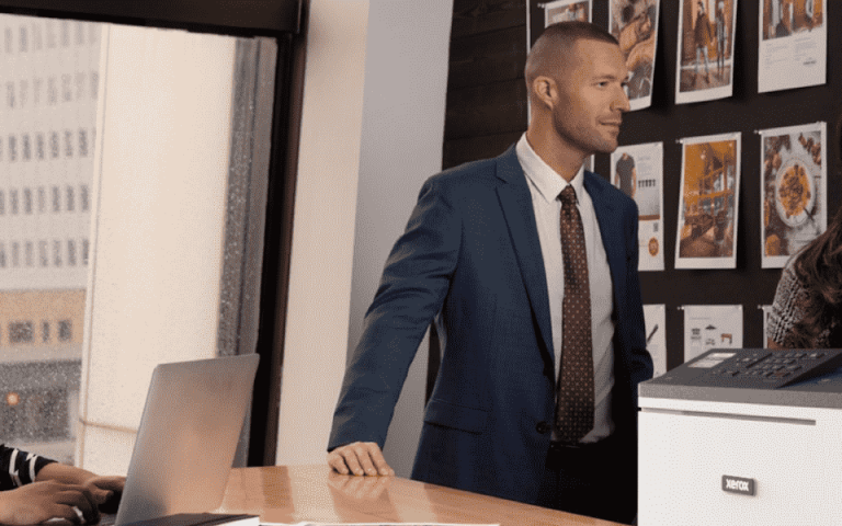 Three people working in an office next to the Xerox C310 printer
