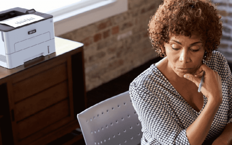 A person sitting at a desk with the Xerox B230 in the background