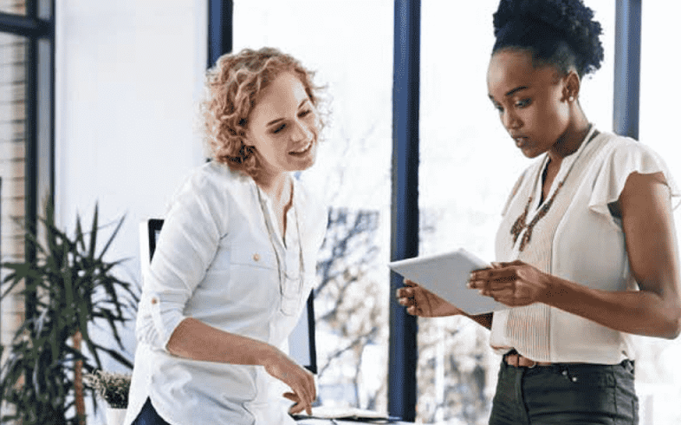 Two people looking at documents with the Xerox VersaLink C7020 in the background