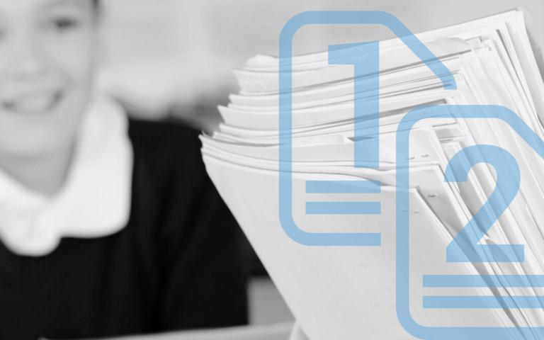 A teacher handing out organized and stacked papers to a classroom 