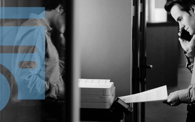 A man using a printer while on the phone