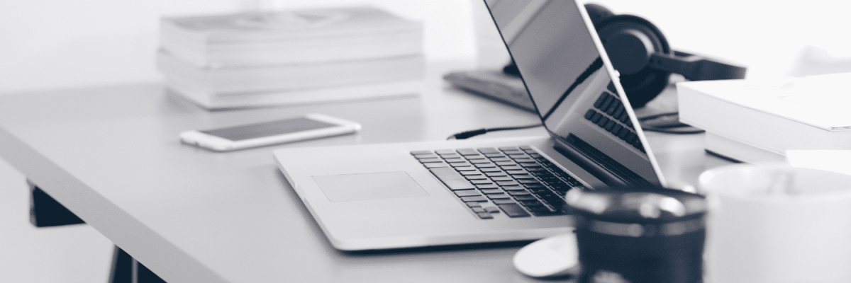 A picture of a desk with a laptop halfway open, a phone and books