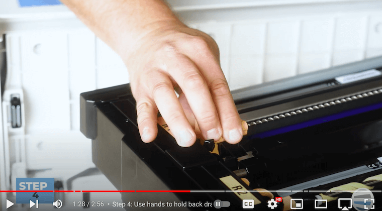 Printer technician grabs the 2 orange blocks on the ends of the corotron assembly on the Xerox PrimeLink C9065