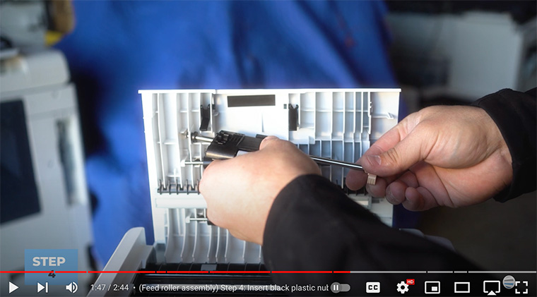 Printer technician inserts black dowel of feed roller into  Xerox VersaLink C410/C415