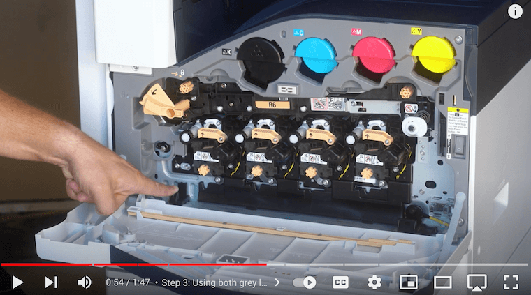 Printer technician points out the black foot holders where the new waste cartridge will go on the Xerox VersaLink C7030