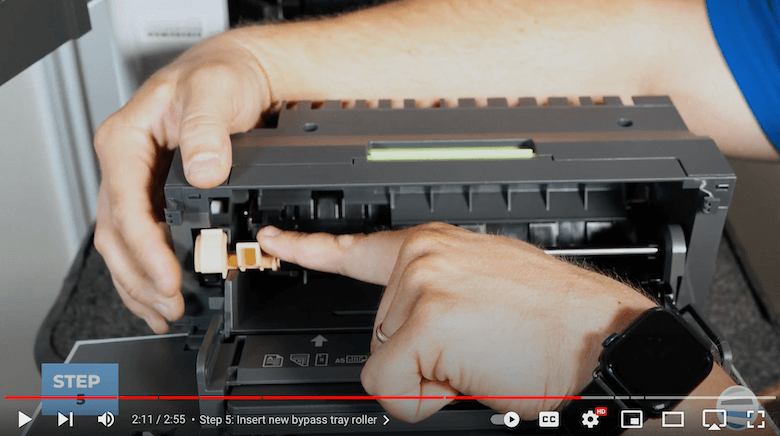 A printer technician pushes down the new bypass tray roller kit on the VersaLink B625