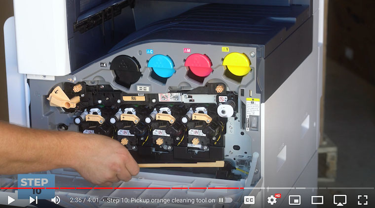 Printer technician grabs orange cleaning tool on front cover of the Xerox VersaLink C7020/C7025/C7030
